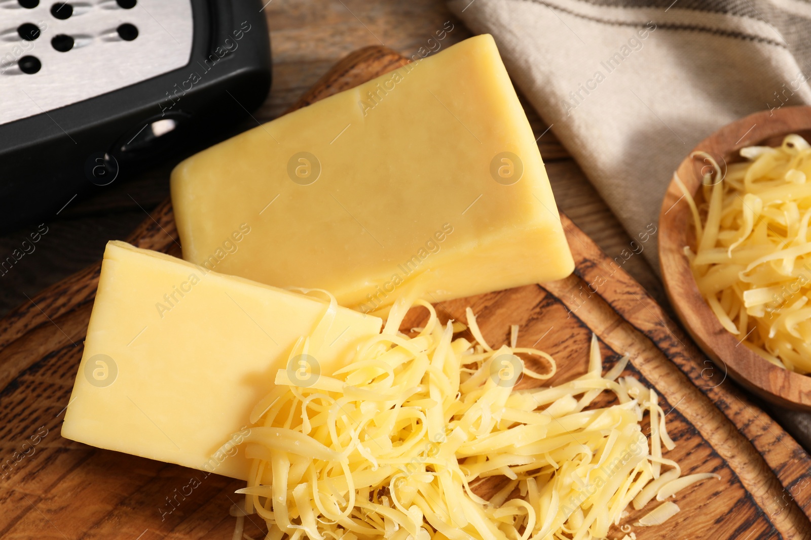 Photo of Grated and whole pieces of cheese on wooden table, closeup