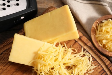 Grated and whole pieces of cheese on wooden table, closeup