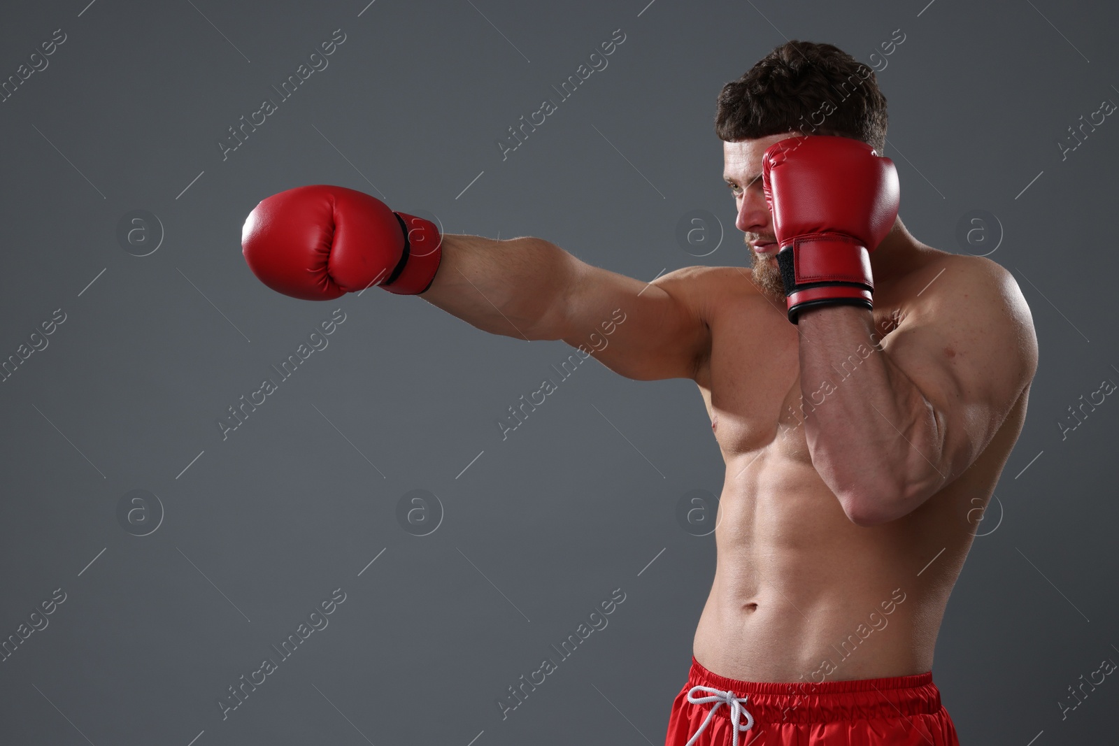 Photo of Man in boxing gloves fighting on grey background