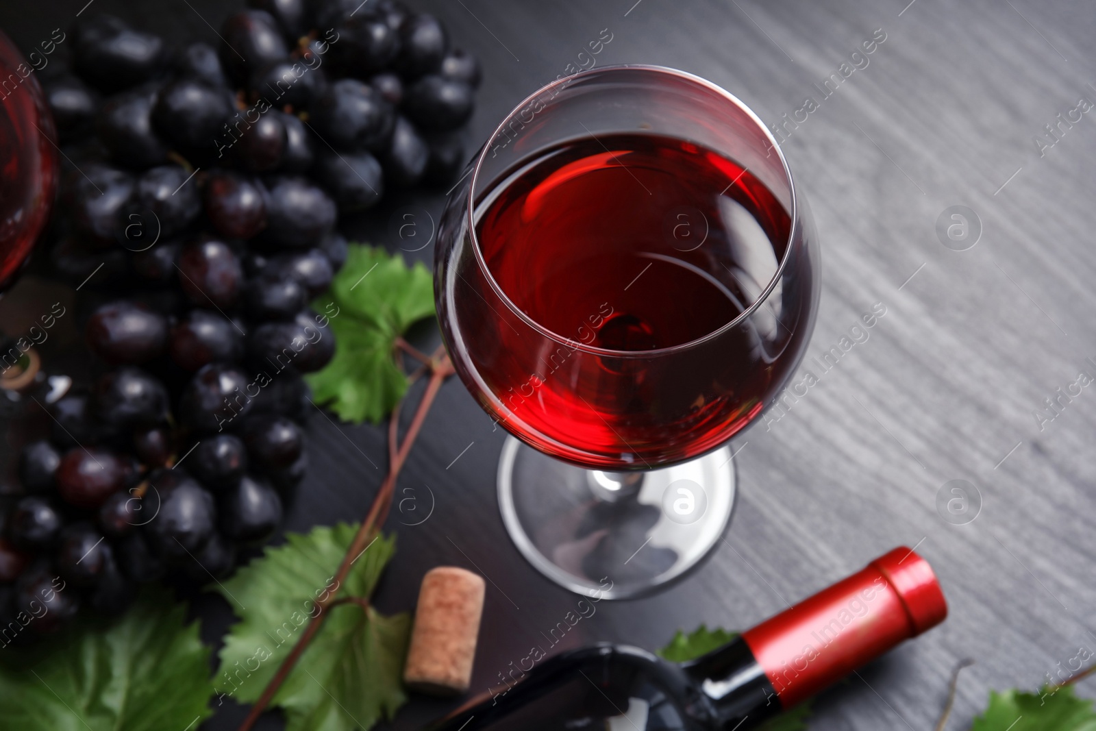 Photo of Glass and bottle of red wine and fresh ripe juicy grapes on table