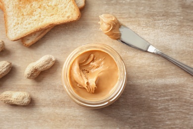 Photo of Jar with creamy peanut butter on table