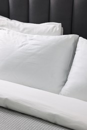 Photo of Soft white pillows and duvet on bed, closeup