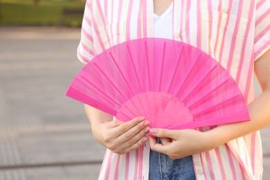 Photo of Woman with pink hand fan outdoors, closeup