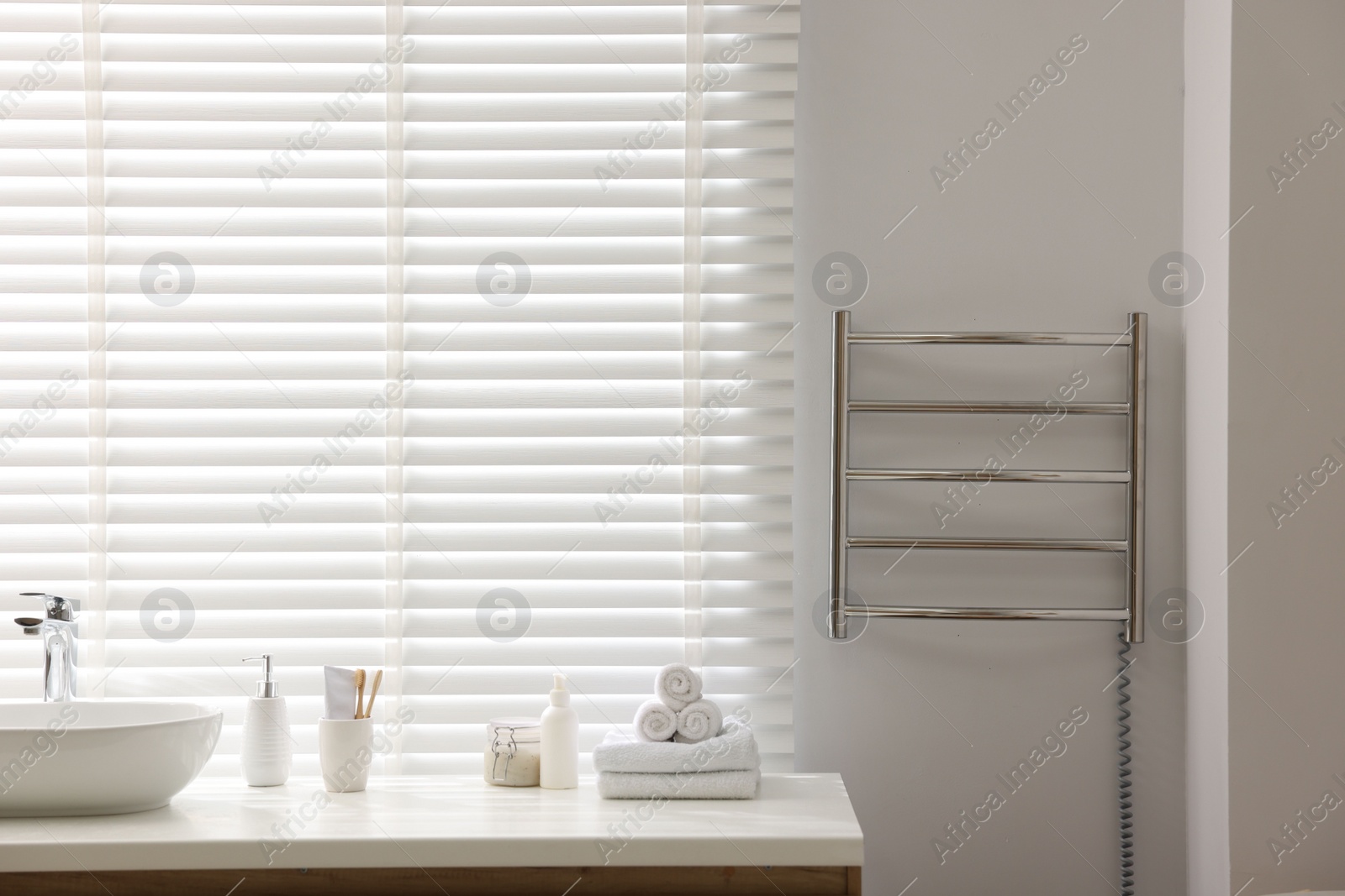 Photo of Heated towel rail on white wall in bathroom, space for text