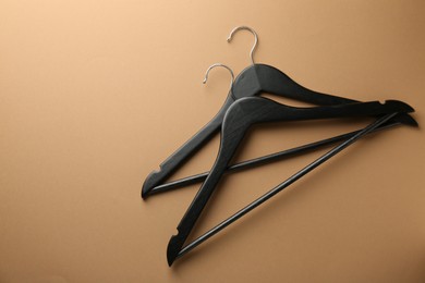 Photo of Black hangers on brown background, top view. Space for text