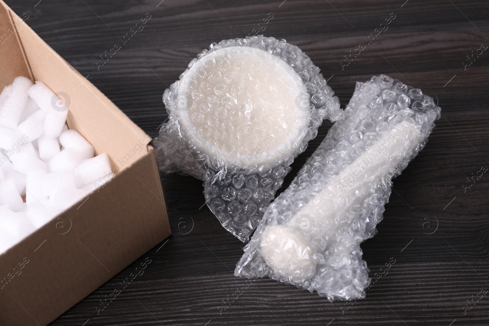 Photo of Mortar and pestle packed in bubble wrap on dark wooden table