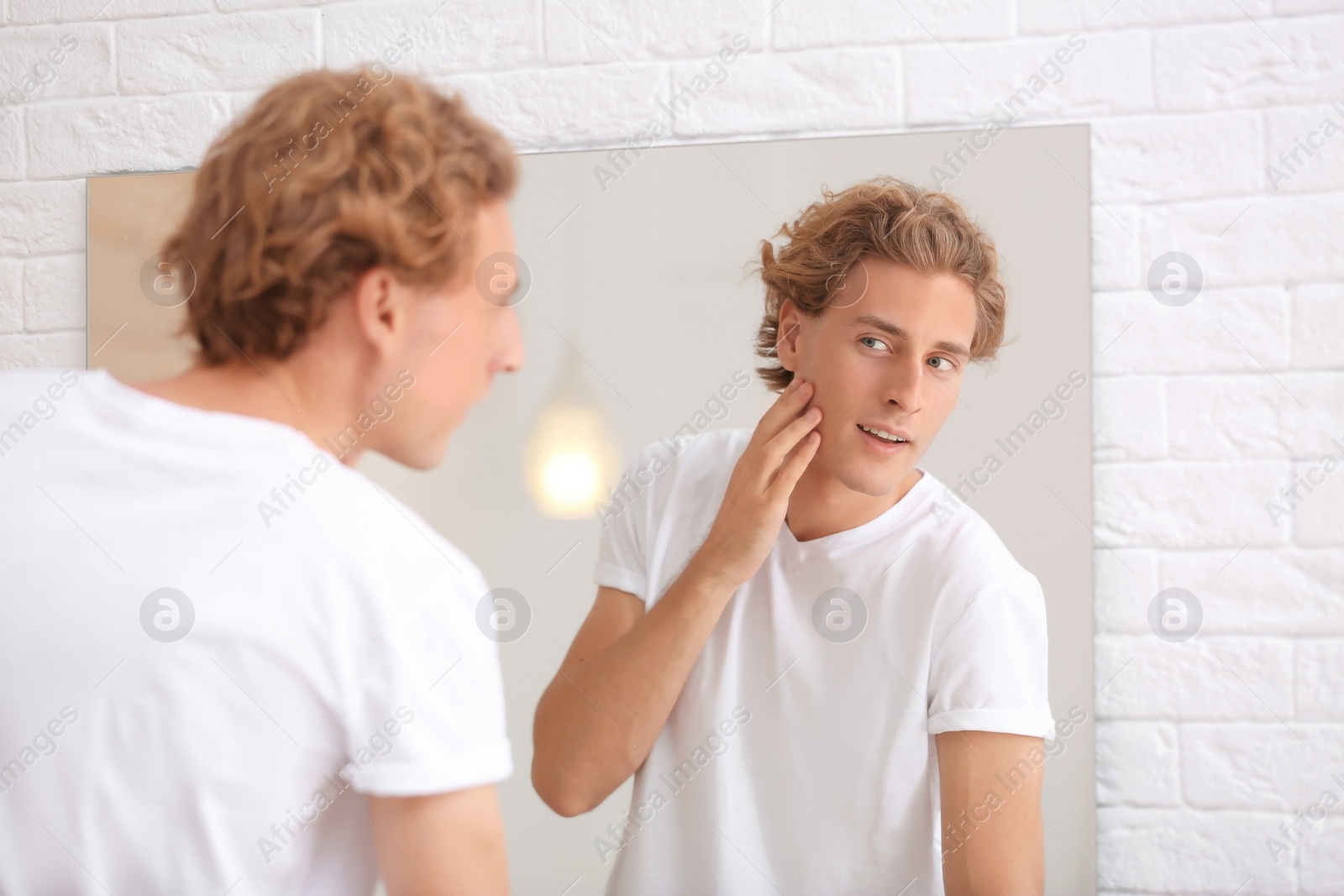 Photo of Young man looking in mirror after shaving at home