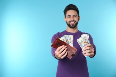 Photo of Happy young man with money on color background. Space for text