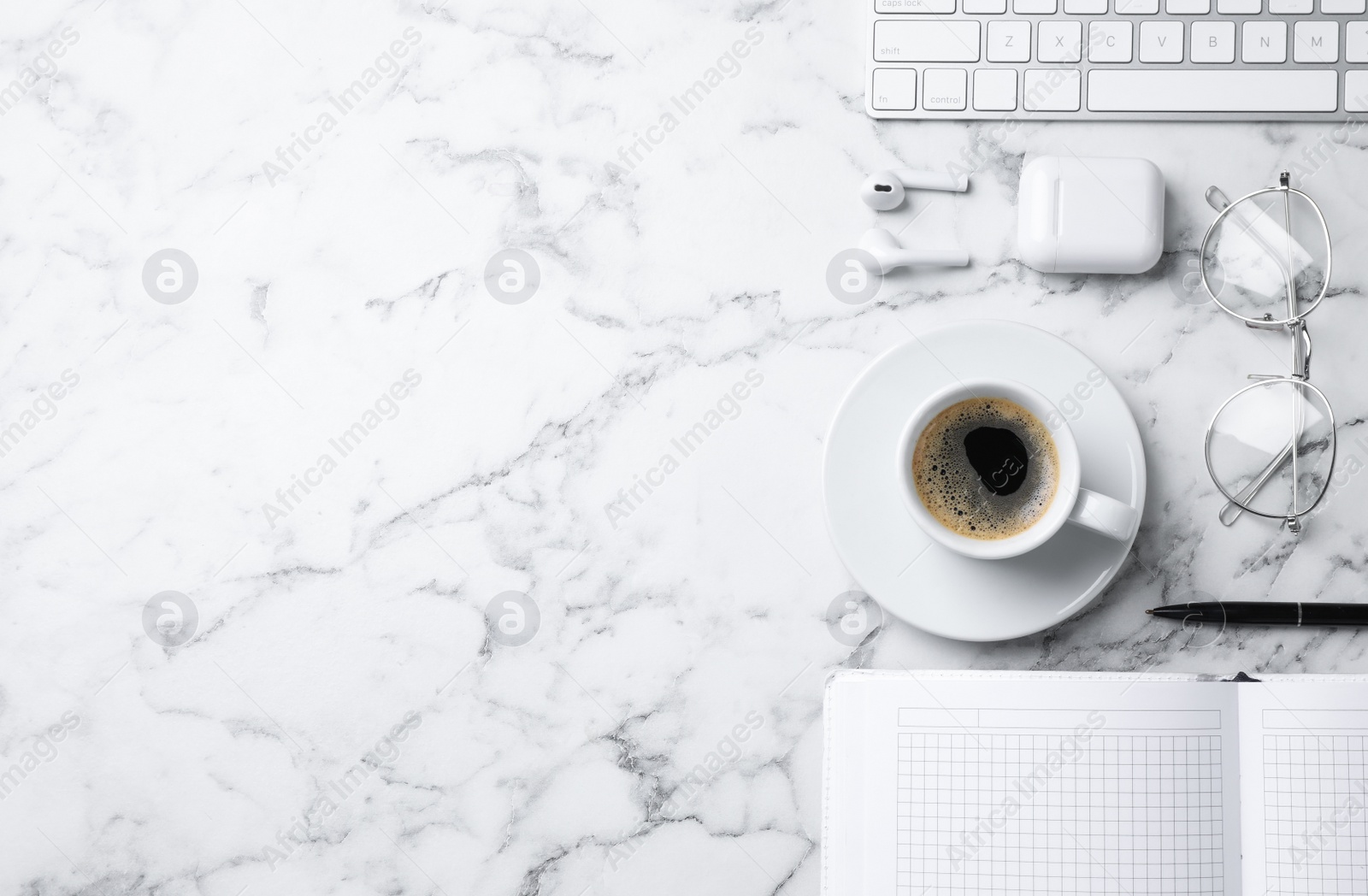 Photo of Flat lay composition with cup of coffee, earphones and stationery on white marble table