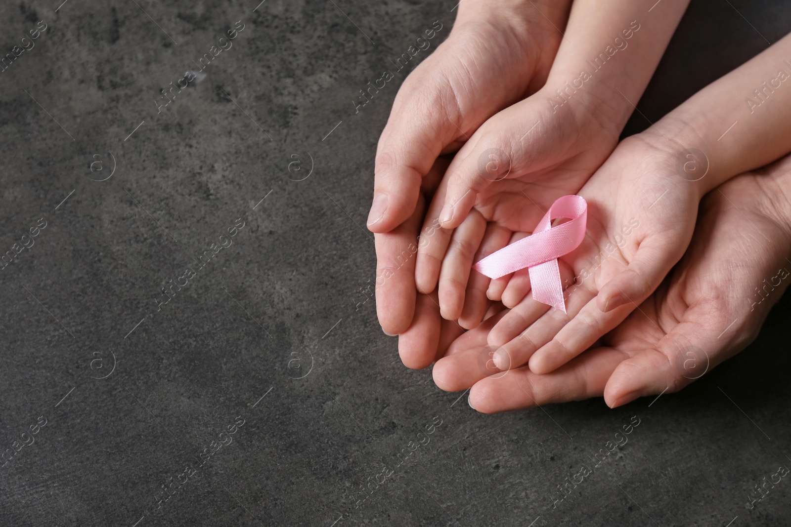 Photo of Woman and girl holding pink ribbon on grey background, top view with space for text. Breast cancer awareness