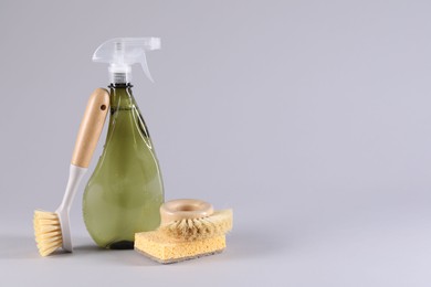 Photo of Bottle of cleaning product, sponge and brushes on light grey background. Space for text