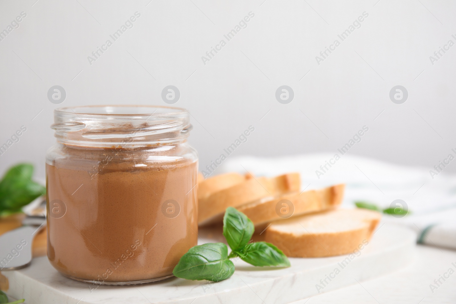 Photo of Delicious meat pate, fresh bread and basil on white table. Space for text