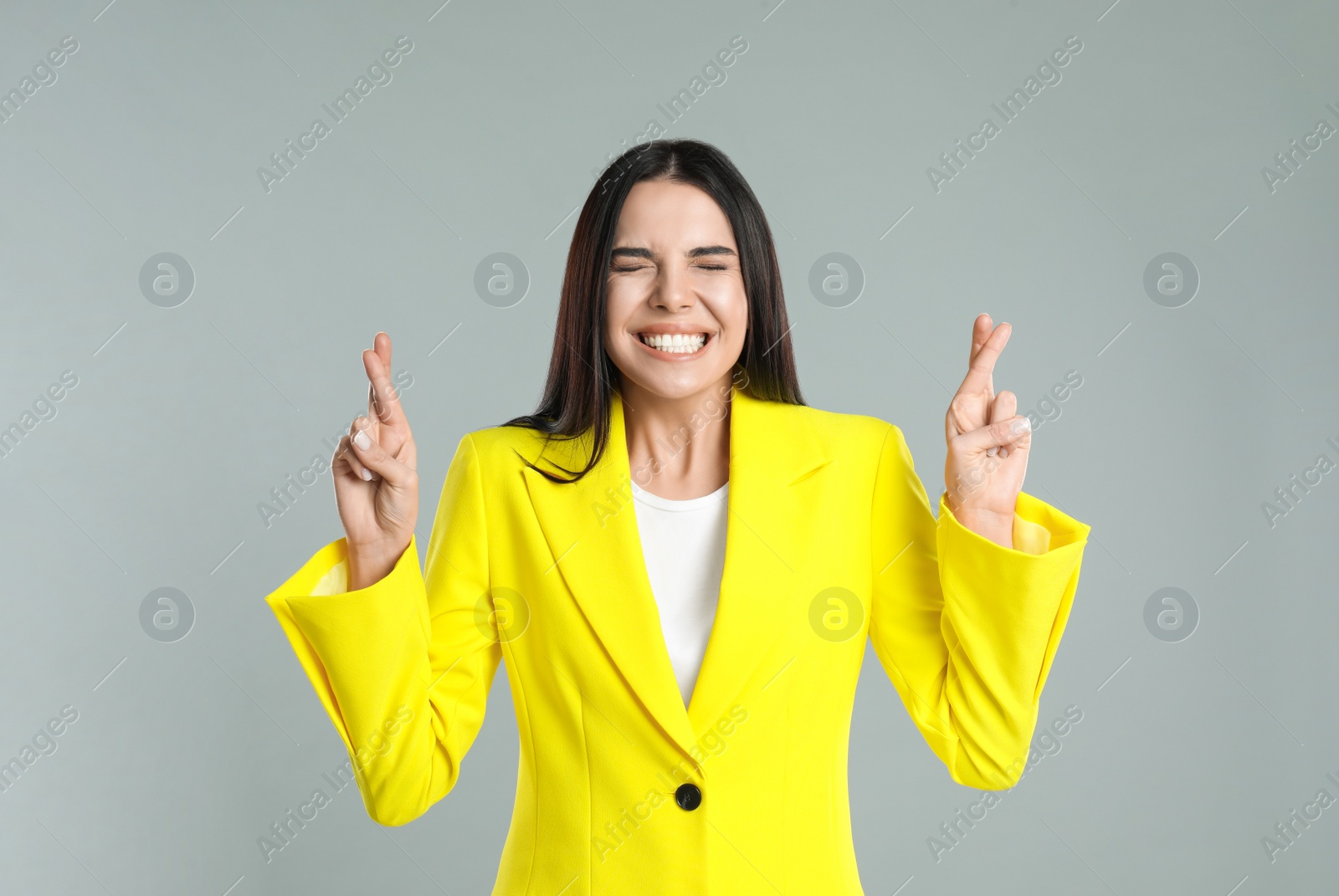 Photo of Woman with crossed fingers on grey background. Superstition concept