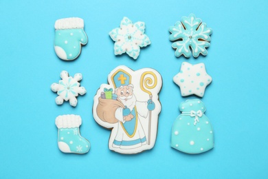 Photo of Tasty gingerbread cookies on light blue background, flat lay. St. Nicholas Day celebration