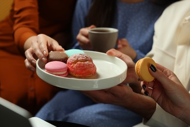 Photo of People eating sweet macarons in cafe, closeup