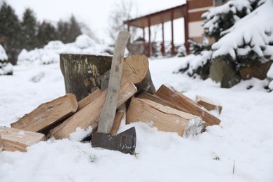 Photo of Axe, chopped wood and wooden log outdoors on winter day