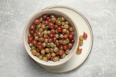 Photo of Fresh ripe gooseberries in bowl on light grey table, flat lay