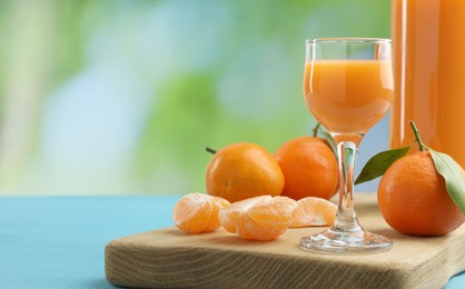 Delicious tangerine liqueur and fresh fruits on light blue table, space for text