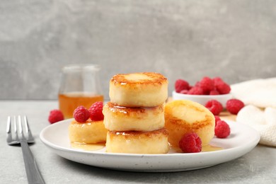 Delicious cottage cheese pancakes with raspberries and honey on light grey table