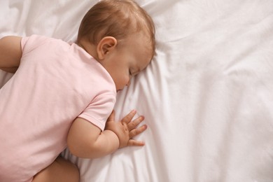 Photo of Adorable little baby sleeping on bed, top view. Space for text