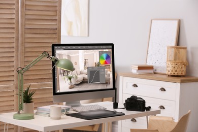 Photo of Retoucher's workplace. Computer with photo editor application, camera and graphic tablet on table in office
