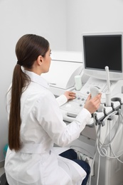 Professional sonographer using modern ultrasound machine in clinic