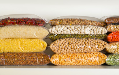 Different types of legumes and cereals in plastic bags on shelf. Organic grains