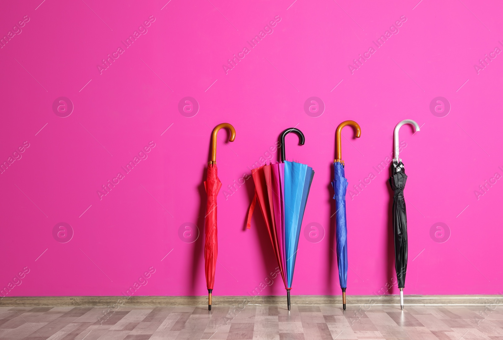 Photo of Beautiful umbrellas on floor near color wall with space for design