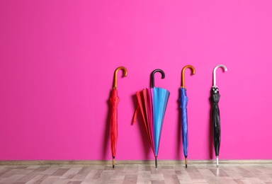 Beautiful umbrellas on floor near color wall with space for design