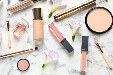 Photo of Many different makeup products and spring flowers on marble background, flat lay