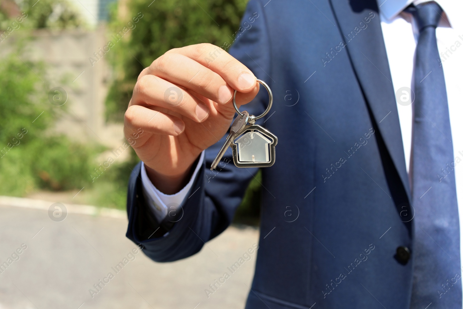 Photo of Real estate agent holding key outdoors, closeup