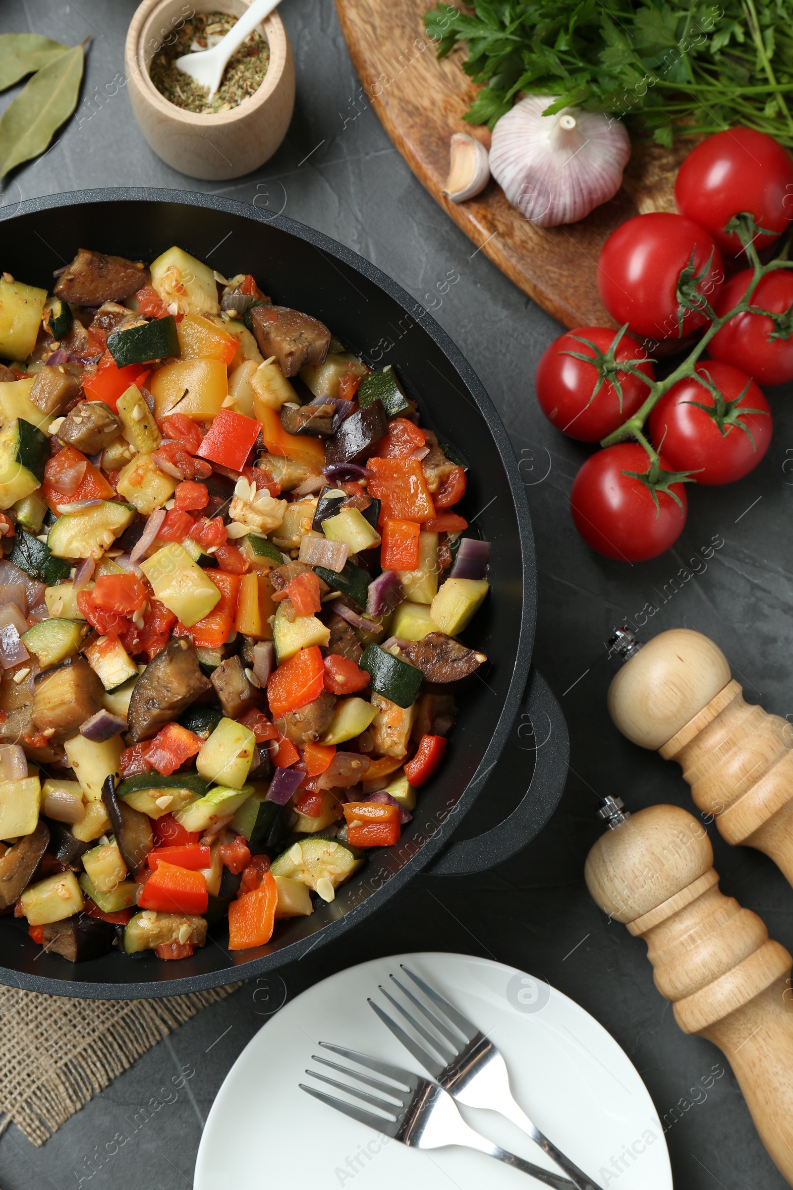 Photo of Delicious ratatouille and ingredients on grey table, flat lay