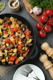 Photo of Delicious ratatouille and ingredients on grey table, flat lay