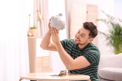 Photo of Man with piggy bank and money at home