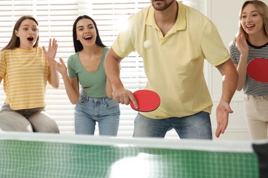 Photo of Happy friends playing ping pong together indoors, closeup