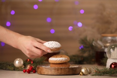 Photo of Woman taking delicious cookie from wooden table, closeup