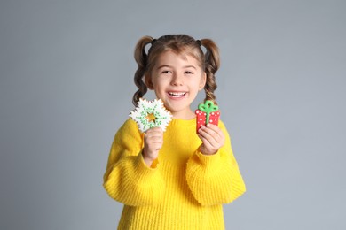 Photo of Cute little girl with Christmas gingerbread cookies on light grey background