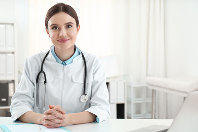 Portrait of young female doctor in white coat at workplace