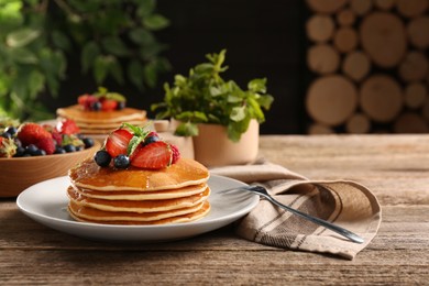 Photo of Tasty pancakes with fresh berries and mint on wooden table. Space for text