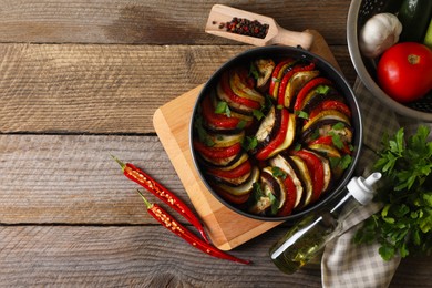 Photo of Delicious ratatouille and ingredients on wooden table, flat lay. Space for text