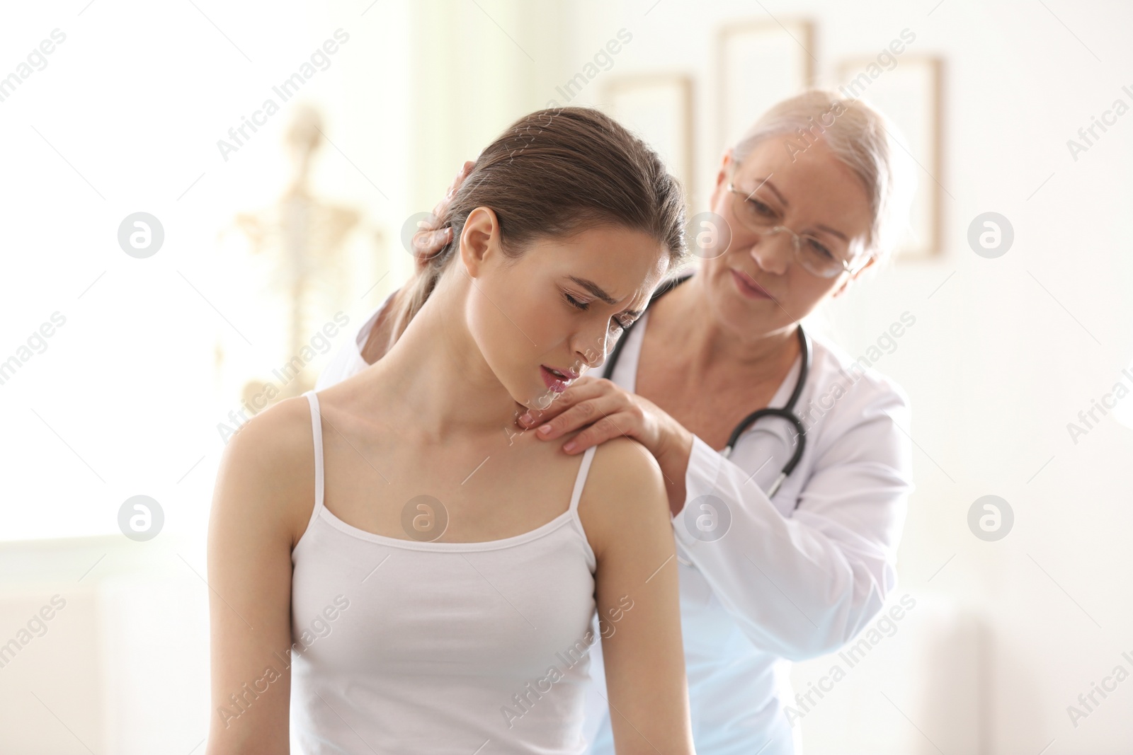 Photo of Female orthopedist examining patient's neck in clinic