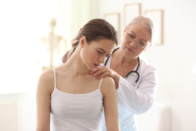 Female orthopedist examining patient's neck in clinic