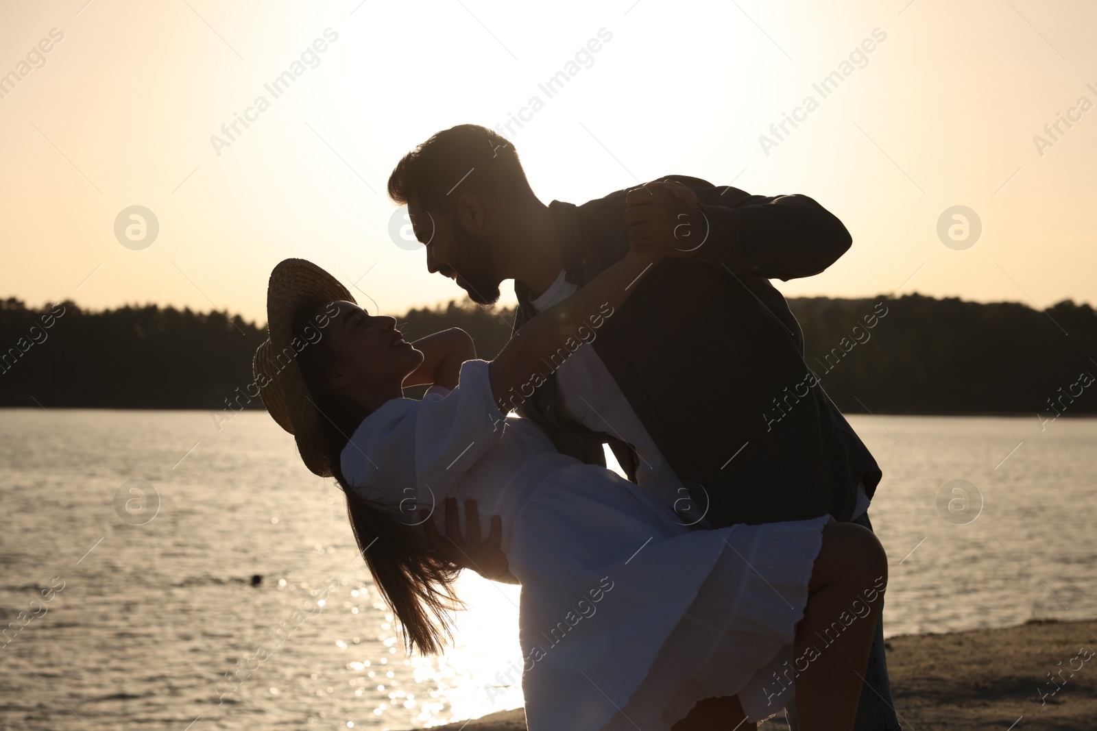 Photo of Happy couple dancing near river at sunset