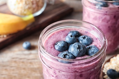 Jar with blueberry smoothie on table, closeup