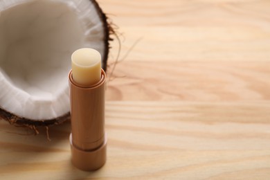 Photo of Lip balm and coconut on wooden table, space for text