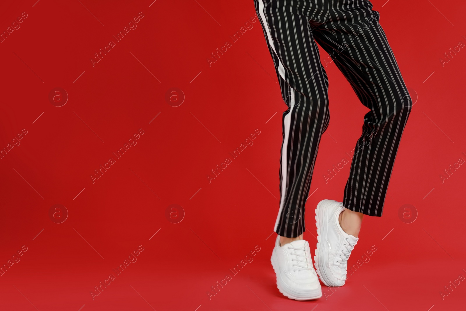 Photo of Woman in stylish sport shoes on red background. Space for text