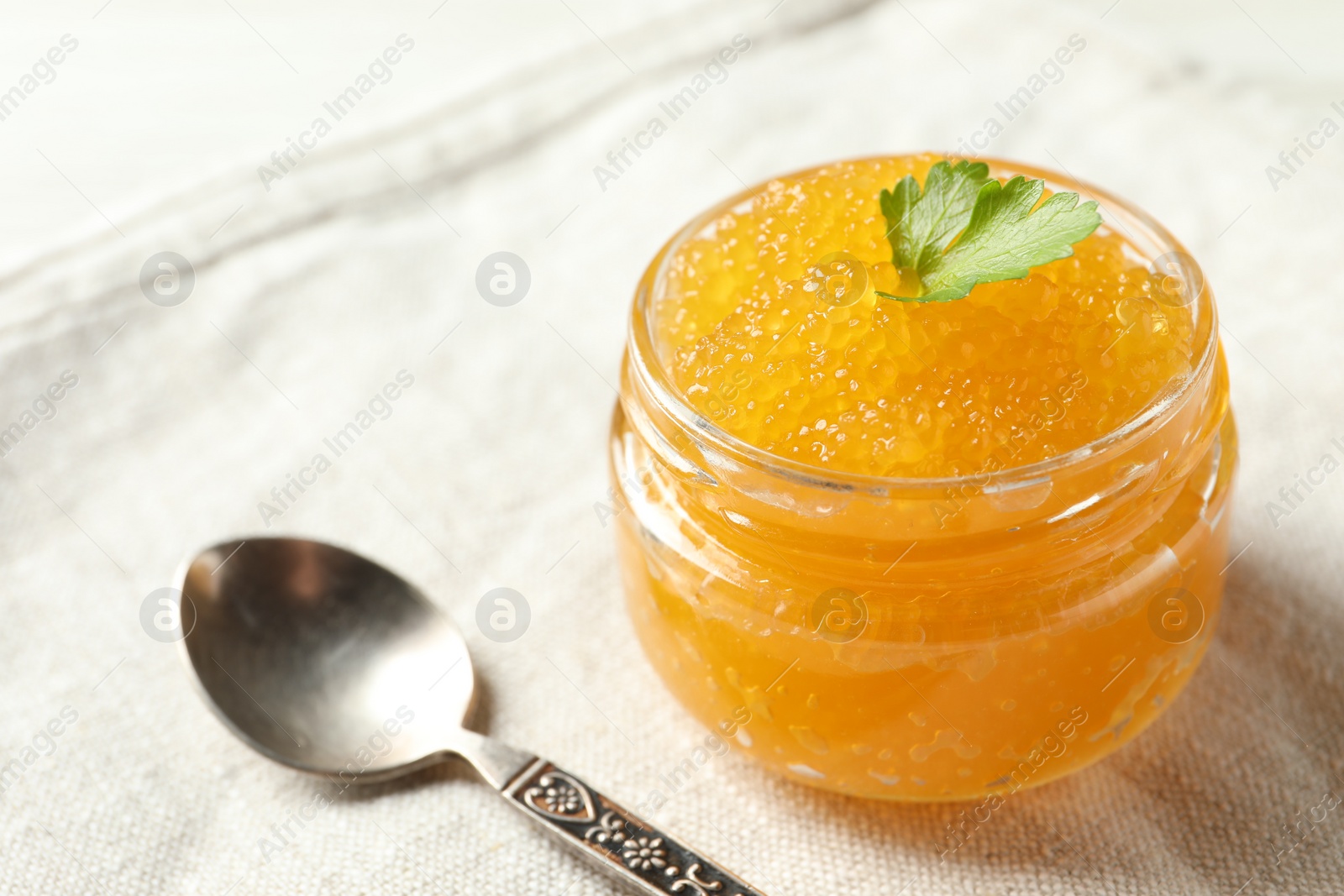 Photo of Fresh pike caviar in glass jar and spoon on table, closeup