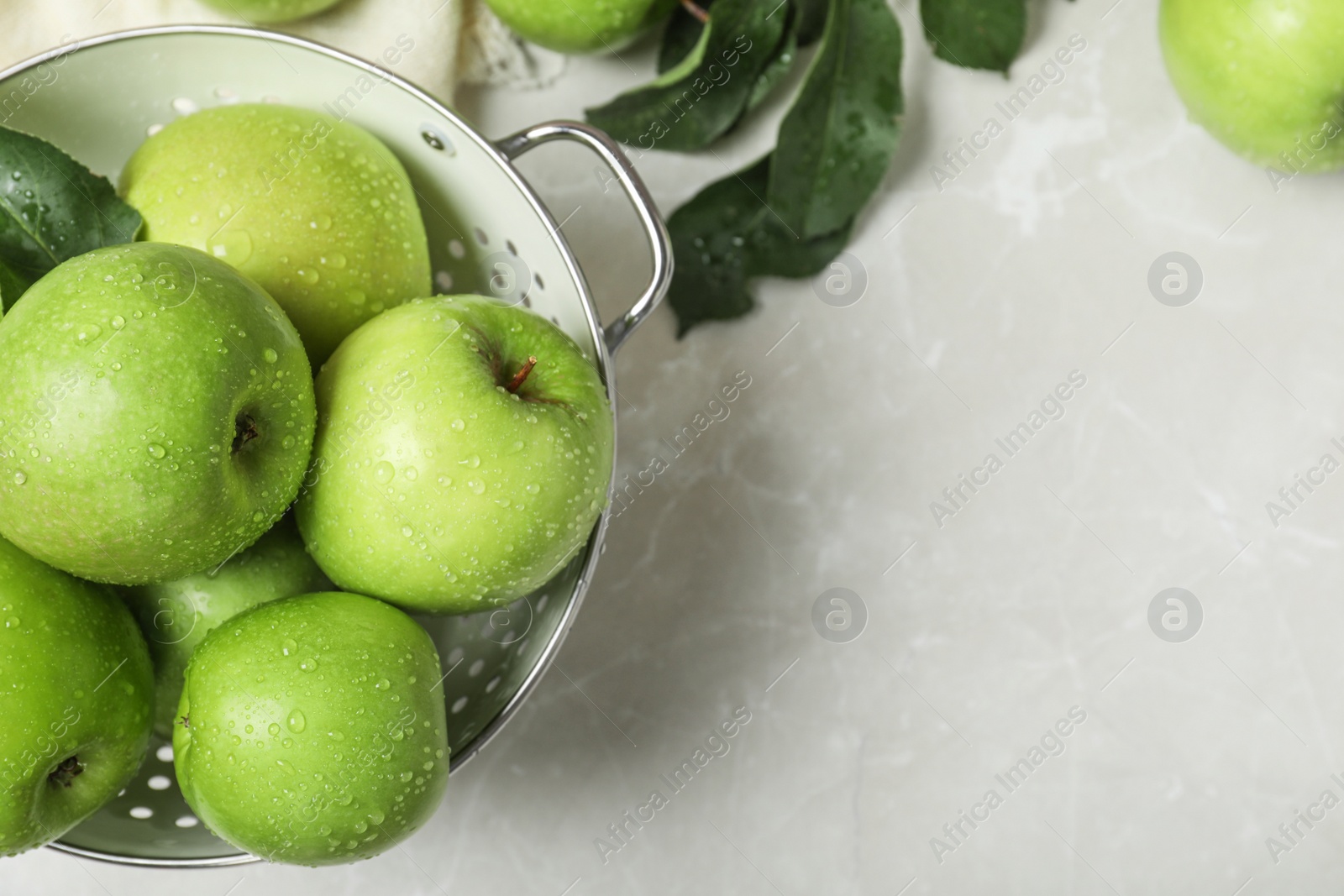 Photo of Juicy green apples in colander and space for text on table