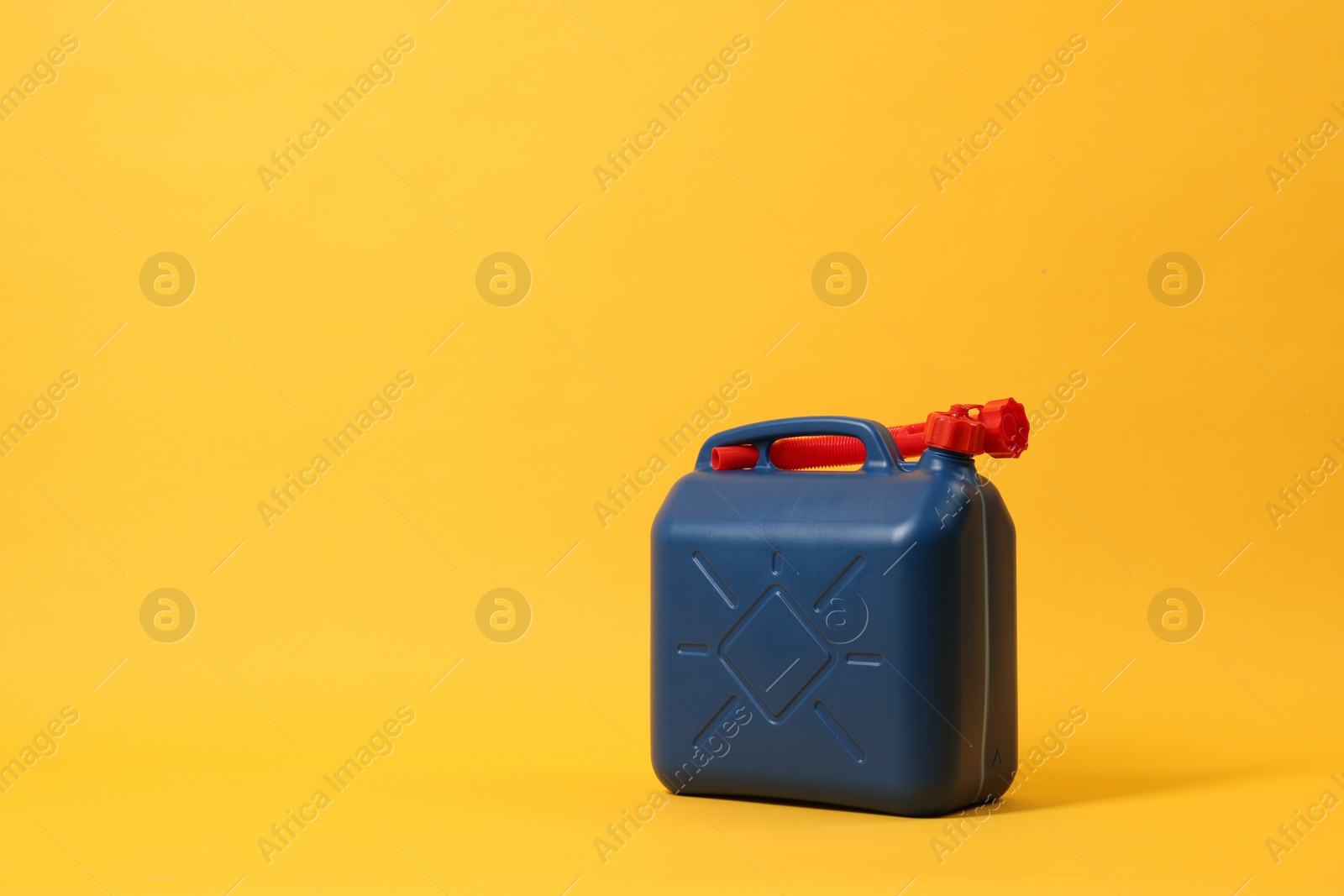 Photo of Blue plastic canister with tube on orange background. Space for text