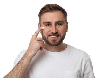 Photo of Happy young man applying facial cream on white background